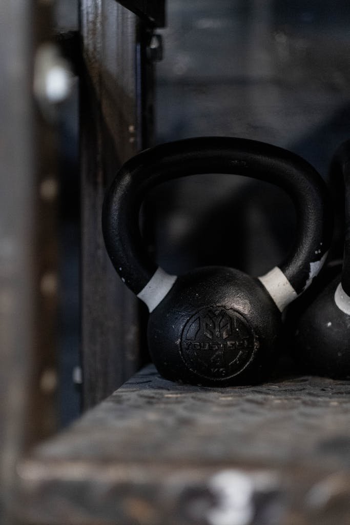 Black kettlebell on a gym shelf, ideal for weightlifting and strength training imagery.
